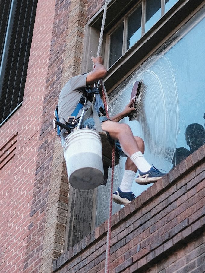 Fensterputzer in Sicherheitsgeschirr reinigt ein Hochhausfenster - Böttger Hausmeisterservice & Objektbetreuung e. K.